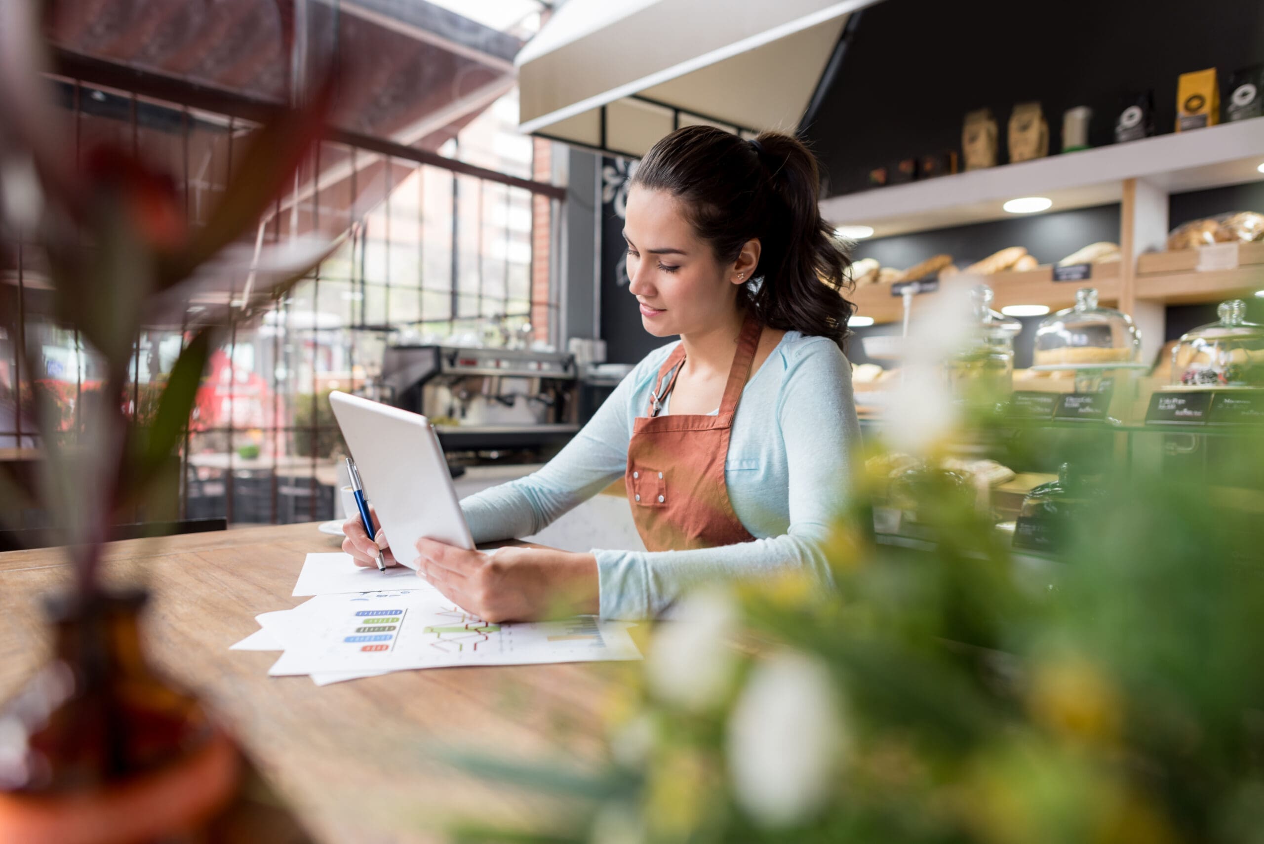 Female barista in coffee shop holding and IPad